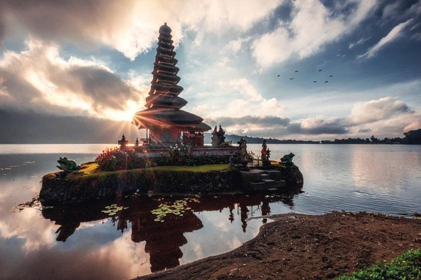 Un temple situé sur une île, dont le reflet se mire dans une eau calme, le tout sous un ciel nuageux. 1