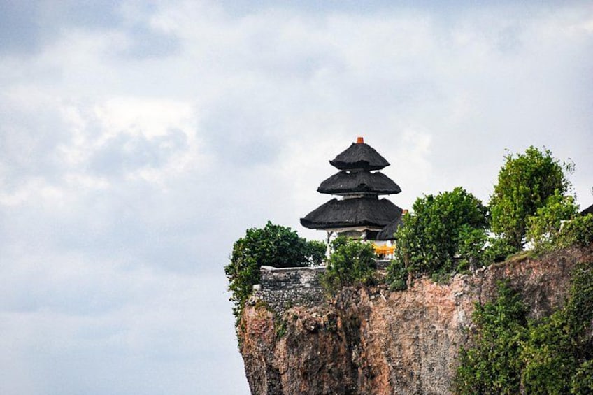 Une pagode perchée sur une falaise, sous un ciel nuageux. 2