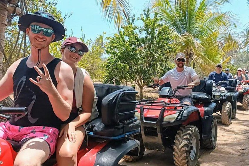 People on ATVs in a tropical setting with palm trees. 1
