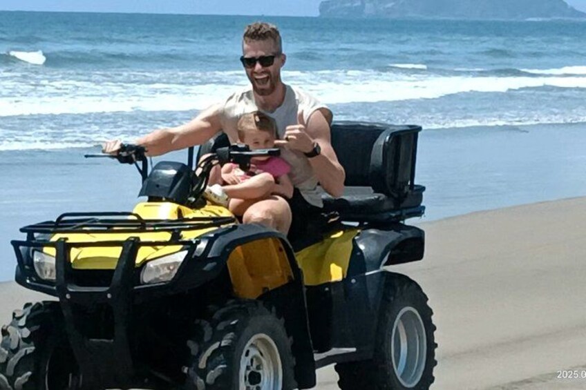 A person driving a yellow ATV on a beach with ocean waves in the background. 2