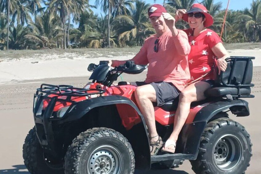 A red ATV on a sandy beach with palm trees in the background. 4