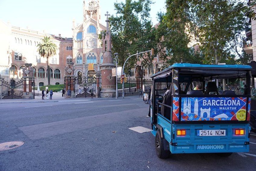 A blue bus with 'BARCELONA WALKTUR' on the back, parked on a street with a historic building in the background. 2