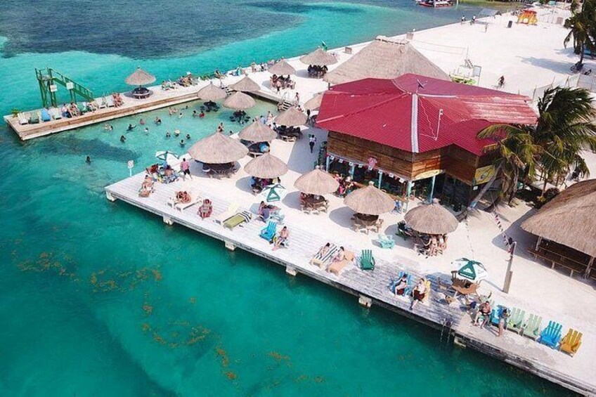 An overwater bungalows with thatched roofs, a pier, and clear turquoise water. 1