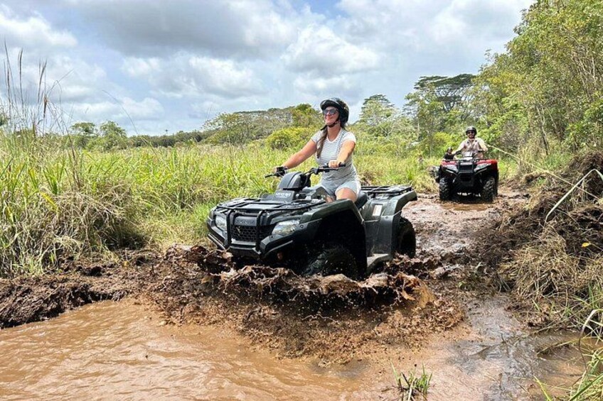 A single-rider ATV powering through muddy trails on our Big Island Farm 3
