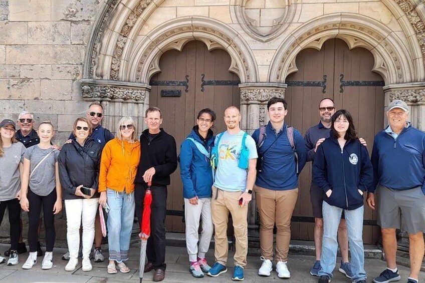 A group of people standing in front of a large, ornate building with a double door. 3