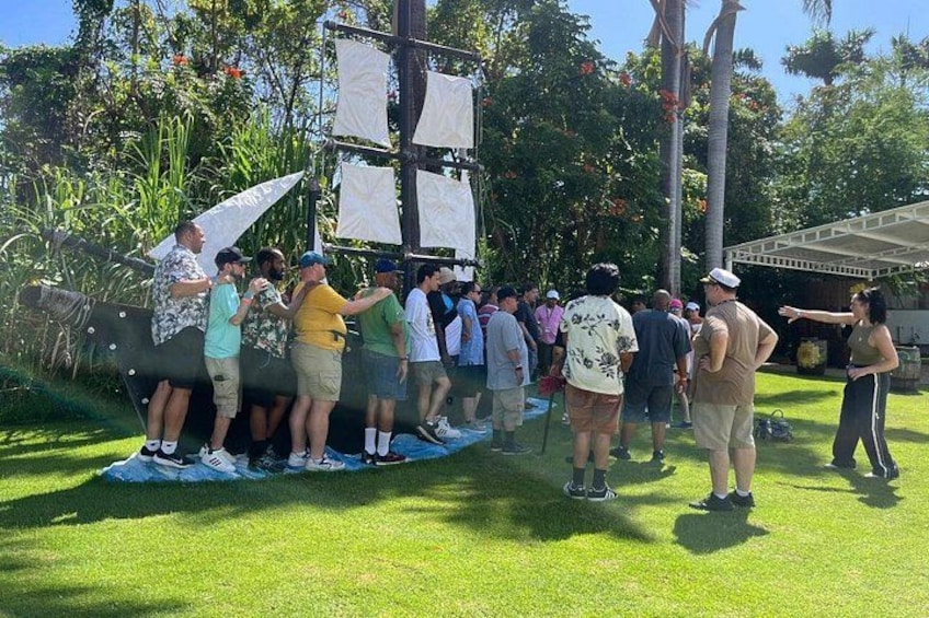 A group of people gathered around a model ship on a grassy field with trees in the background. 4