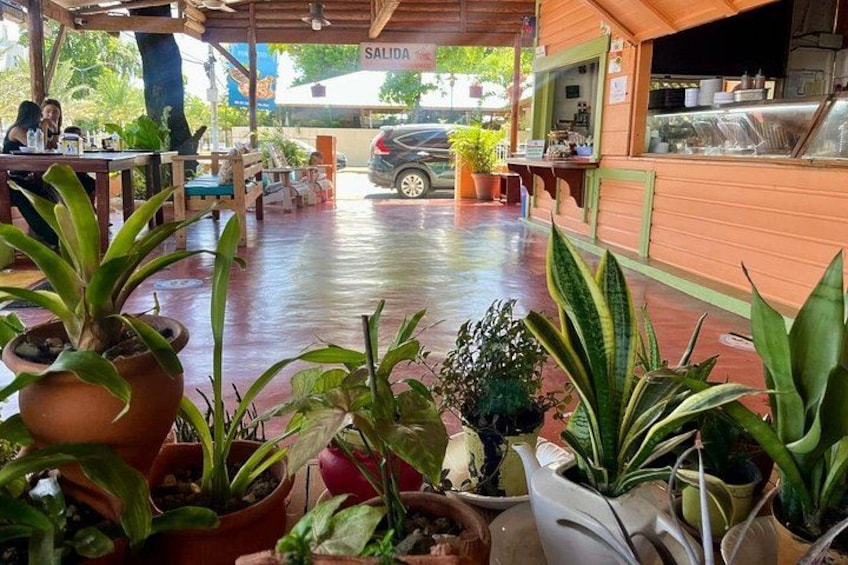 A restaurant patio with potted plants and a car in the background. 5