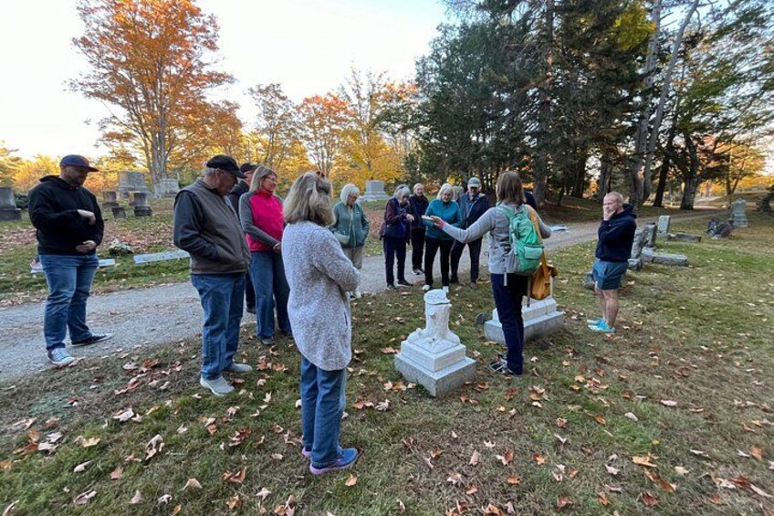 Un grupo de personas en un cementerio, con lápidas y árboles al fondo. 3