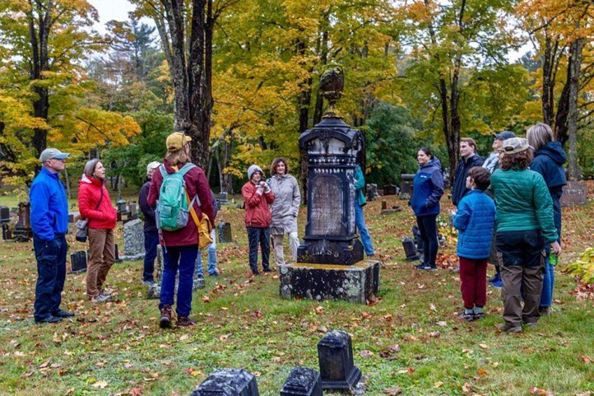 Un grupo de personas junto a un monumento histórico en un parque con follaje otoñal. 1