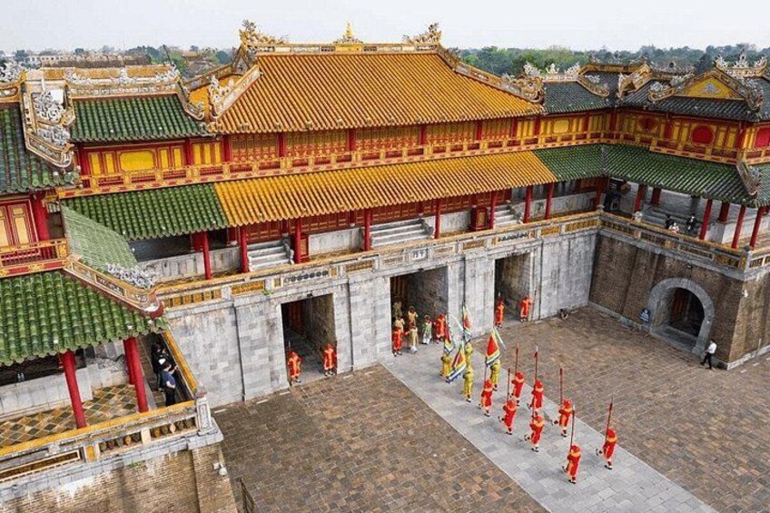 A traditional Chinese building with a courtyard, red-roofed structures, and people in ceremonial attire. 2