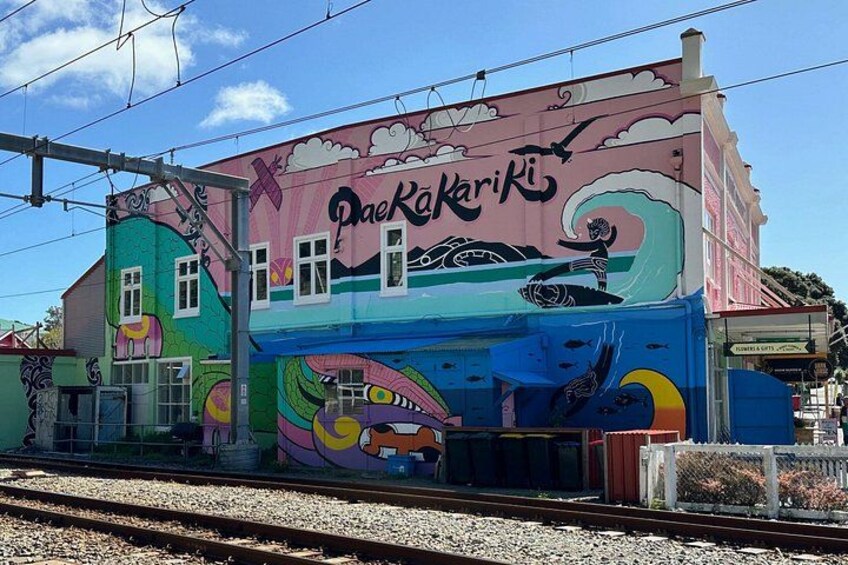 A colorful mural on a building with the text 'Paekakariki' and a train track in the foreground. 4