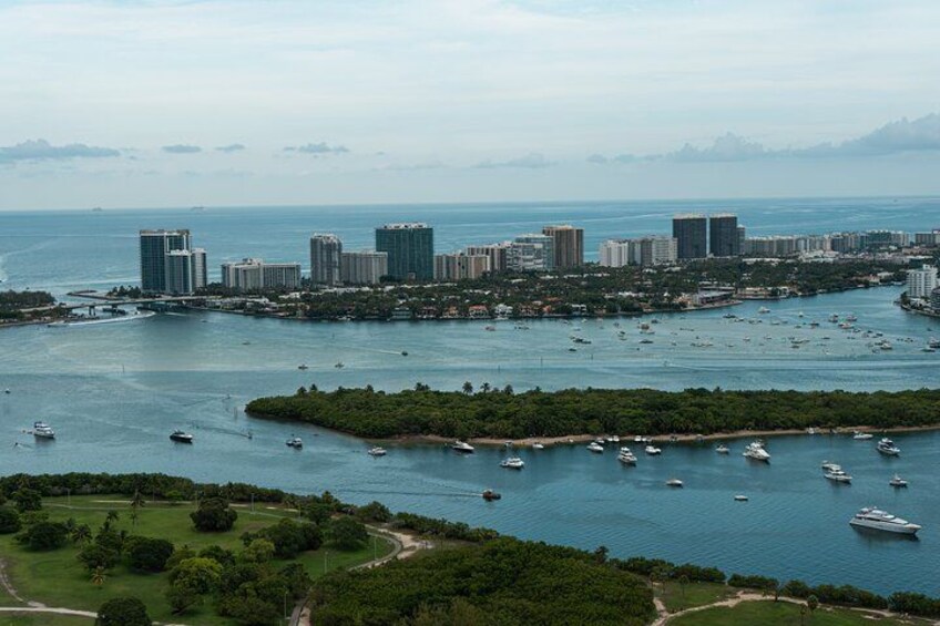 A coastal cityscape with a marina filled with boats, surrounded by greenery and high-rise buildings. 5
