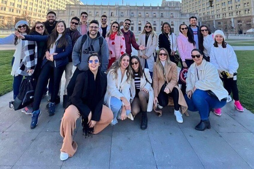 A group of people posing in front of a large building with columns. 1