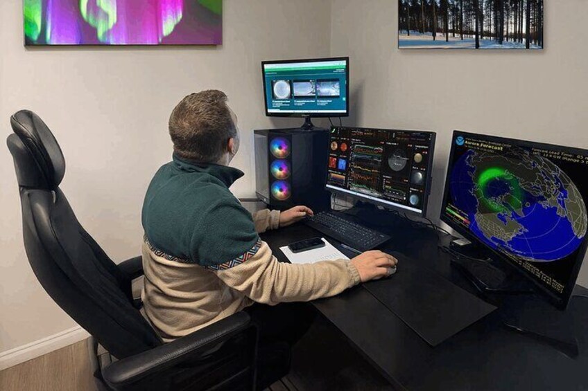 A person working at a desk with multiple computer monitors displaying various data and maps. 2
