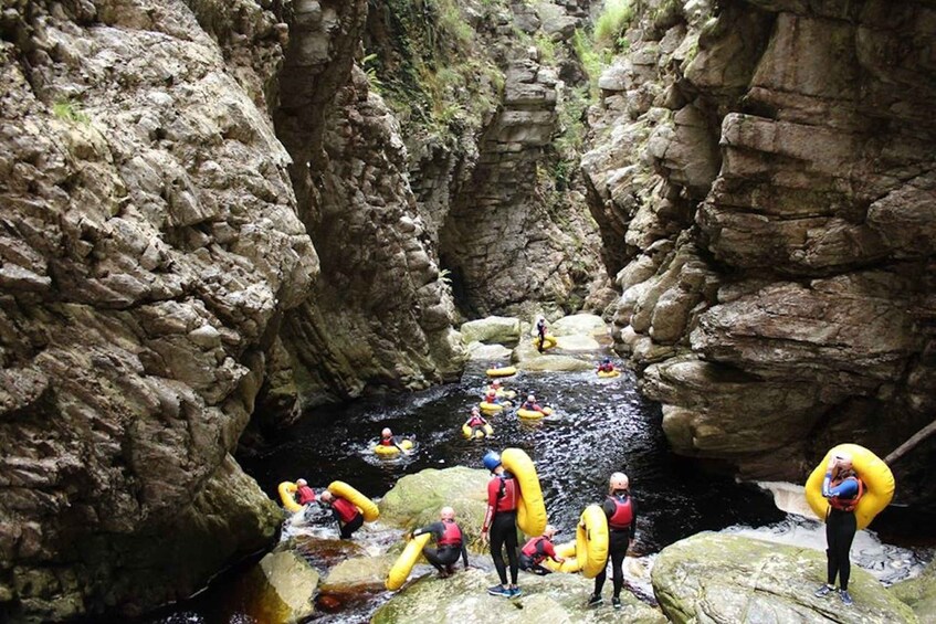 People rafting in a narrow canyon with rocky walls. 2