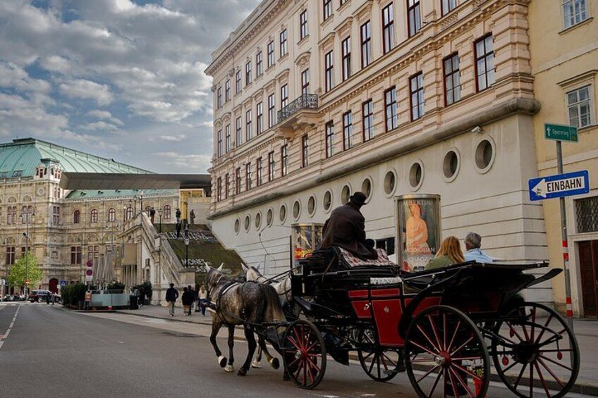 A horse-drawn carriage on a city street with historic buildings in the background. 2