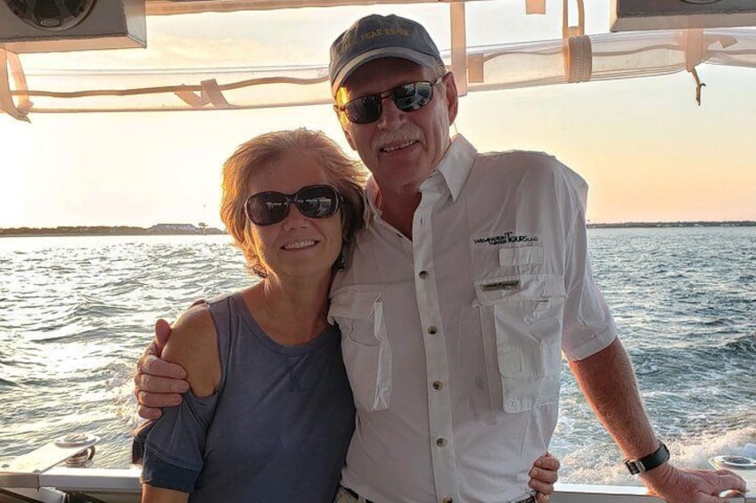 Two people on a boat with a water body and a distant shoreline in the background. 3