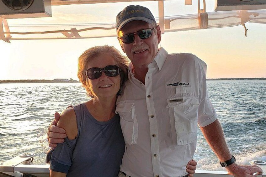 Two people on a boat with a water body and a distant shoreline in the background. 2