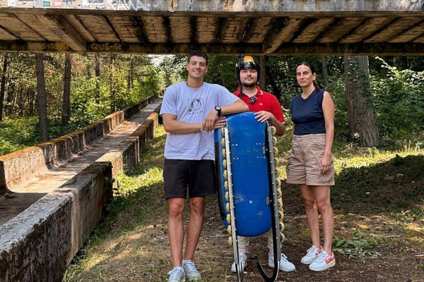 Tres personas de pie bajo una estructura de madera con un objeto azul en primer plano. 4