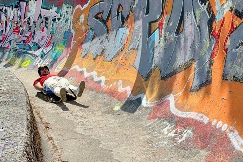 A person sliding down a graffiti-covered ramp. 1