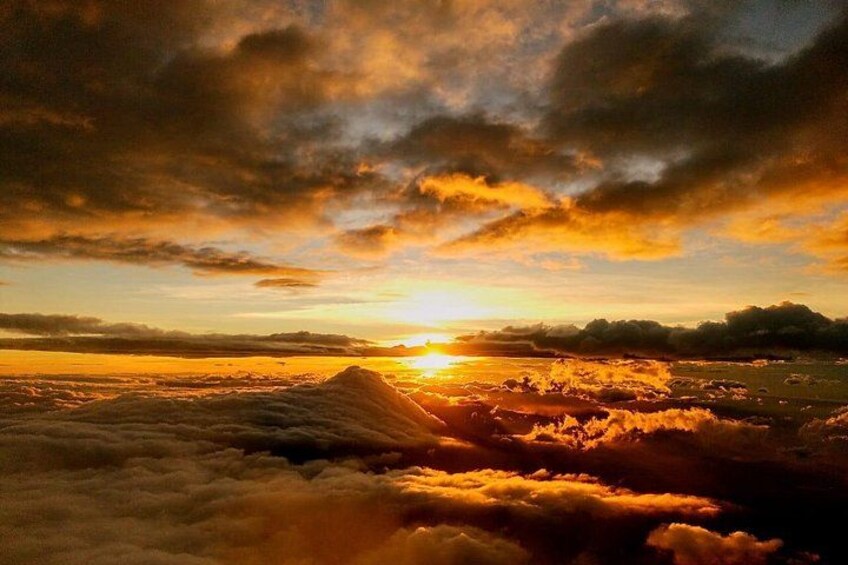 A sunset over a mountainous landscape with clouds below. 3