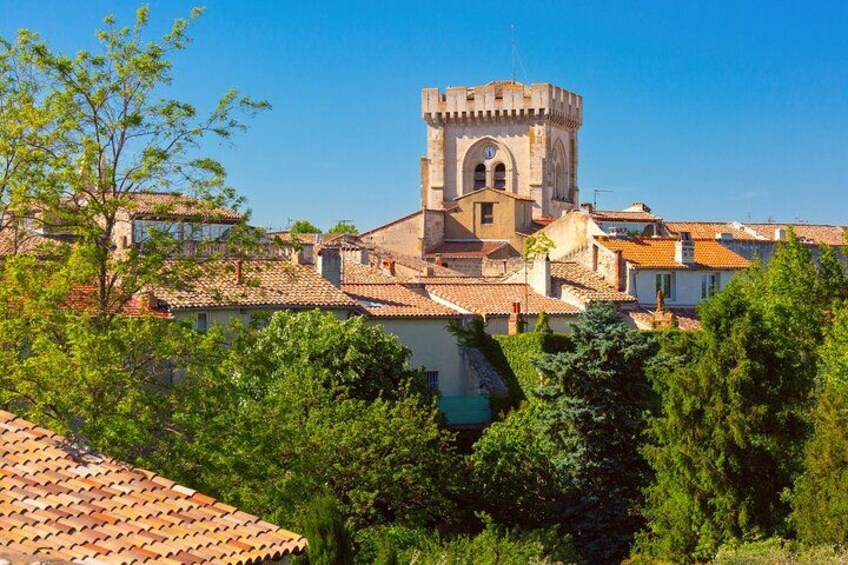 Un'antica torre con orologio, circondata da edifici tradizionali e vegetazione rigogliosa. 4