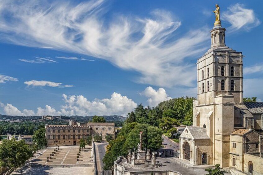 Una chiesa storica con un campanile, un cortile con statue e un cielo azzurro intenso. 5