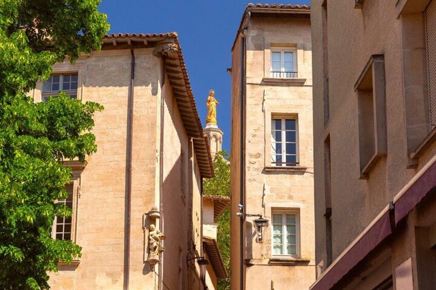 Una stretta via fiancheggiata da edifici, con una statua e un albero. 3