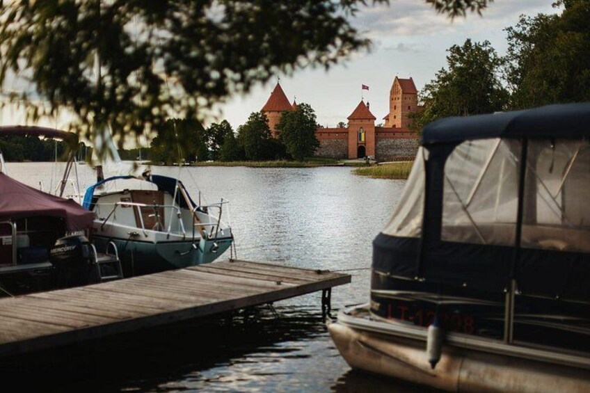 A lake with boats docked, a wooden pier, and a castle in the background. 4