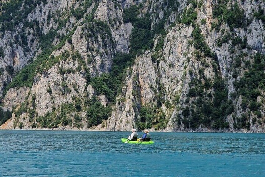 A person kayaking on a calm sea with rocky cliffs in the background. 4