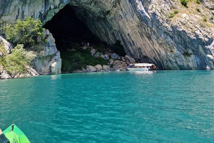 A boat near a rocky cave entrance with clear turquoise water. 2