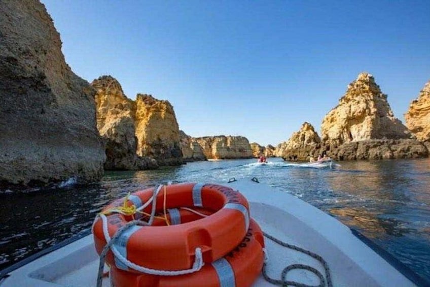 A boat with a life preserver, rocky cliffs, and calm water. 2