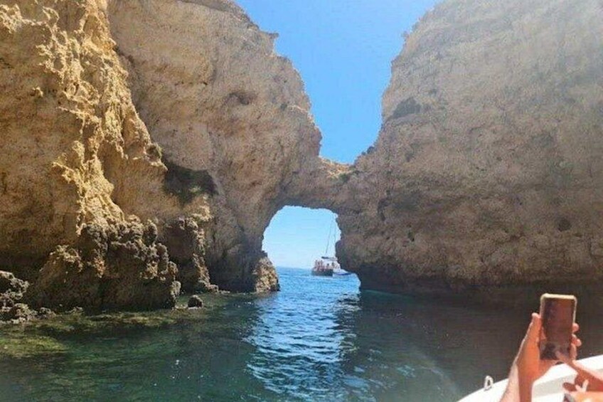 A boat navigating through a natural rock arch formation in a body of water. 5