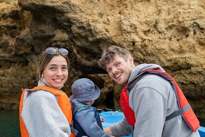 A family on a boat with a rocky cliff in the background. 1