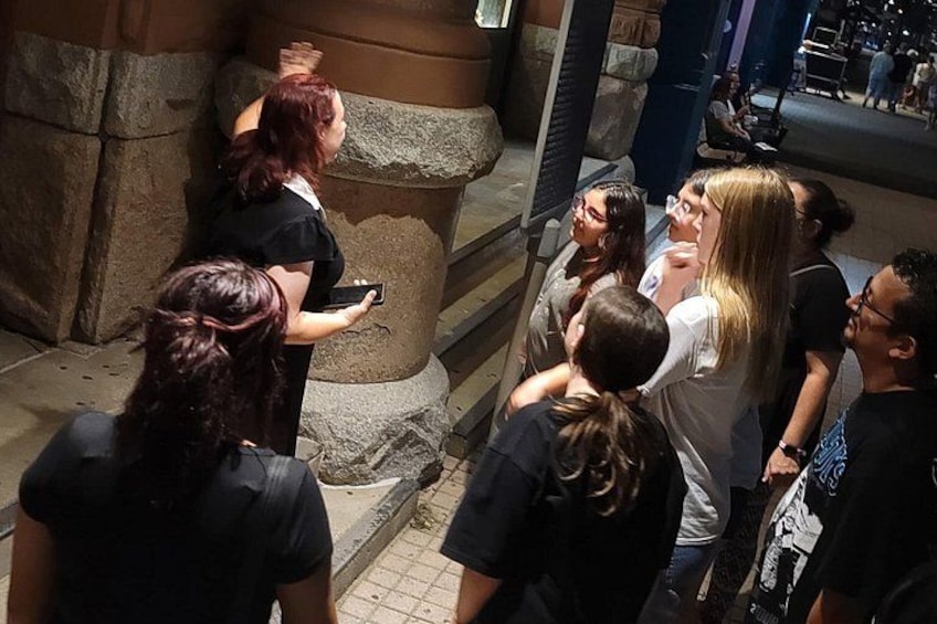 A group of people gathered around a stone pillar in an indoor setting. 5