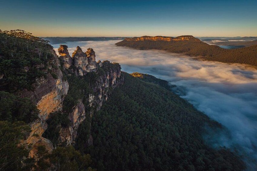 Un paisaje montañoso con formaciones rocosas destacadas y una capa de nubes abajo. 5