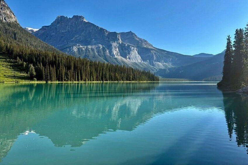 A calm lake with clear reflections of mountains and trees. 3
