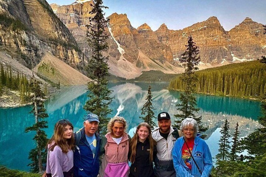 A group of people standing in front of a mountainous landscape with a lake. 4
