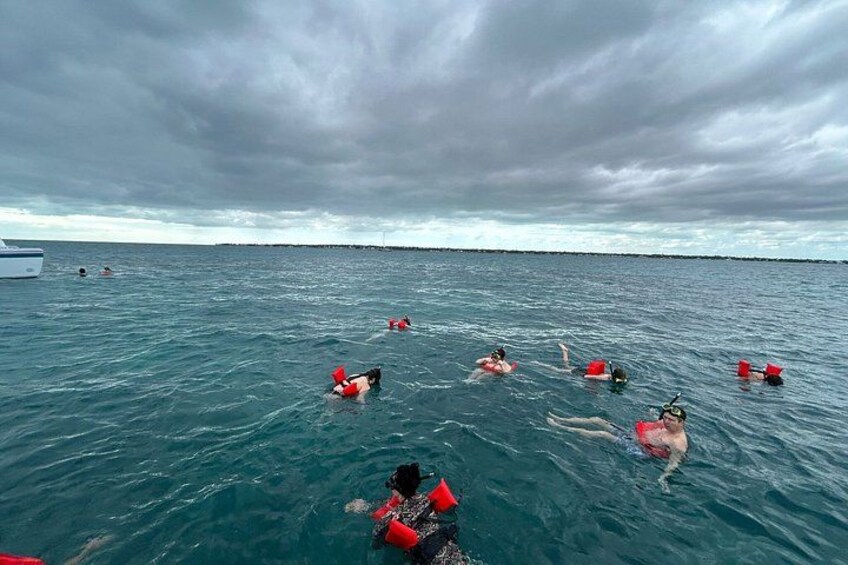 People swimming in the ocean with a boat in the background. 4