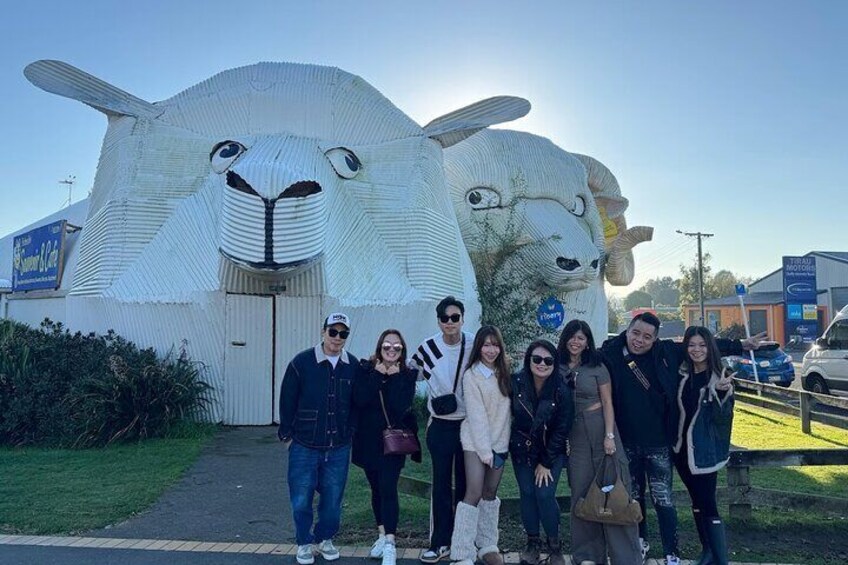 A group of people posing in front of a large sculpture of a sheep. 5