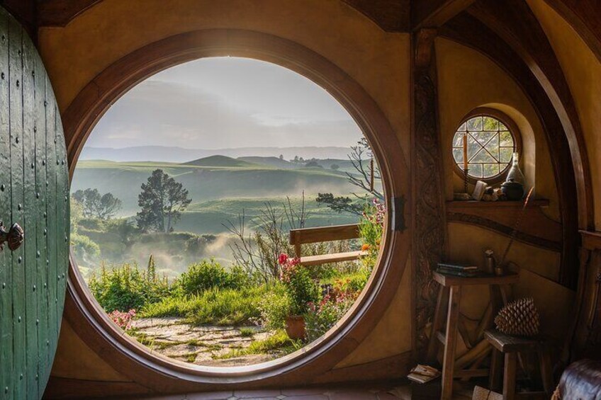 A round window with a view of rolling hills and a rustic interior. 3