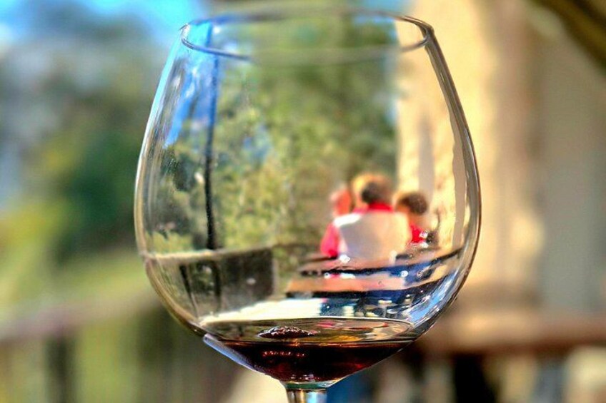A wine glass with a reflection of a person and a boat. 1