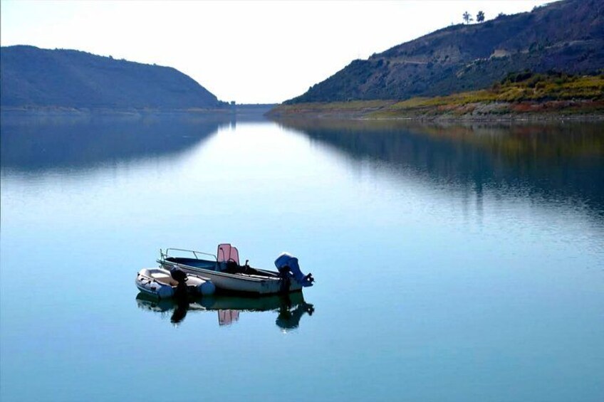 A calm lake with a boat anchored in the center, surrounded by hills. 5