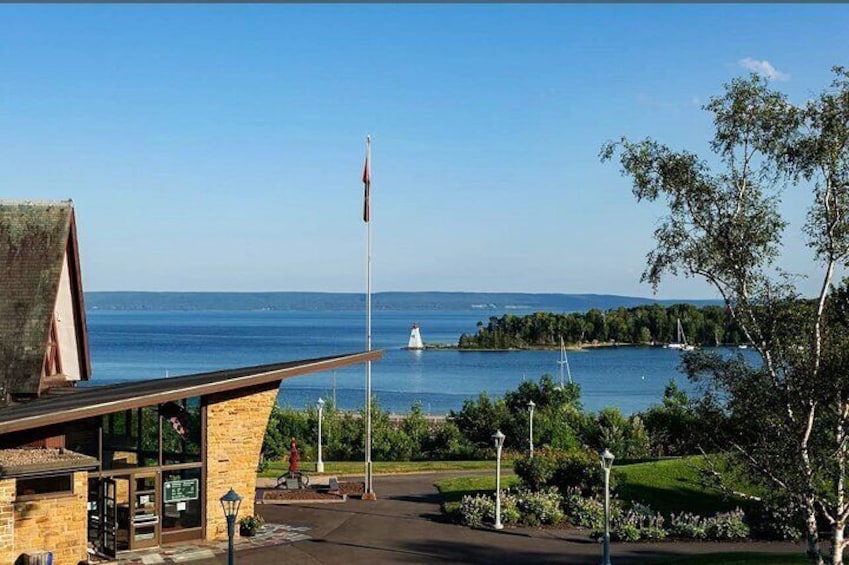 A coastal view with a building, a flagpole, and a distant sailboat. 1