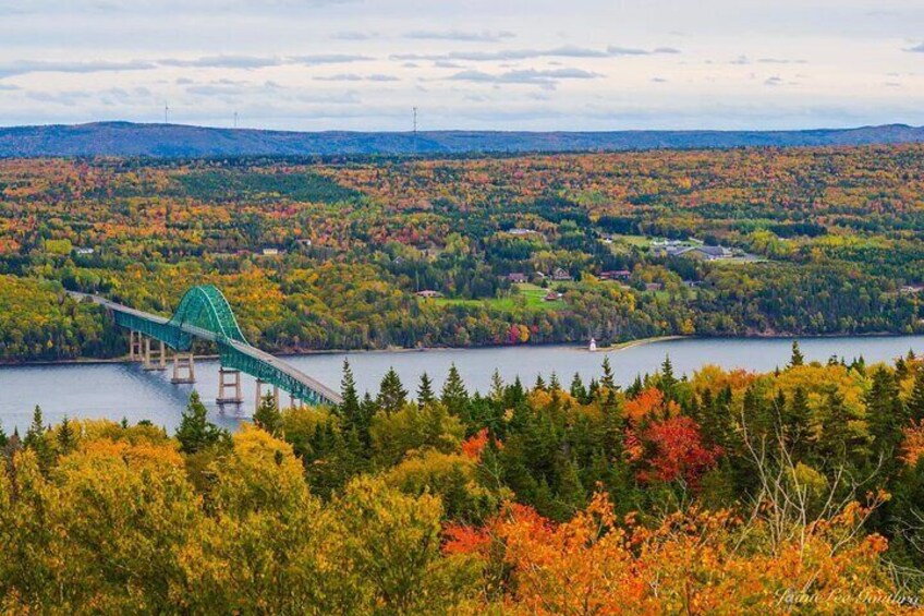 A green bridge over a lake surrounded by autumn-colored trees. 5