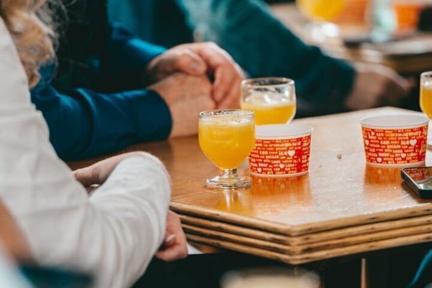 Een houten tafel met een glas sinaasappelsap en een rode beker met witte tekst. 3