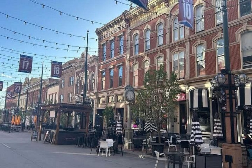 A street with vintage buildings, outdoor seating, and tram lines. 2