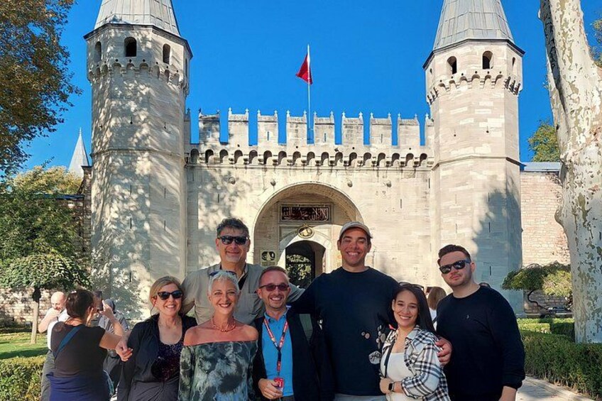 Un groupe de personnes se tient devant un château doté de deux tours et d’un drapeau. 2