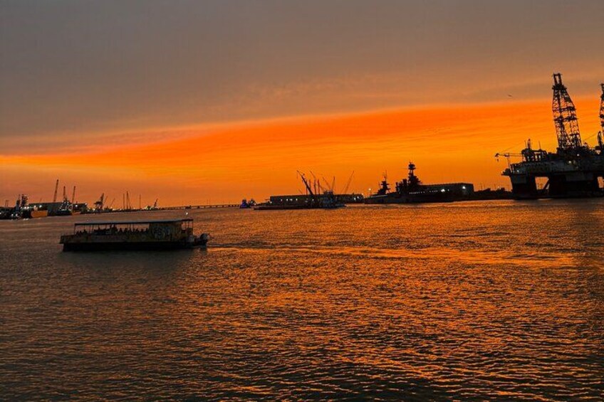 A sunset over a body of water with a boat and an offshore oil platform. 1