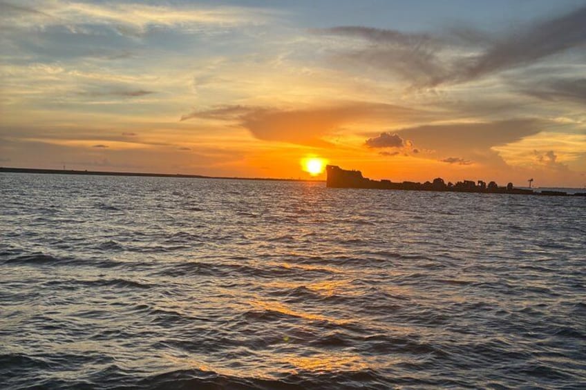 A sunset over a body of water with a silhouette of a city skyline in the distance. 3